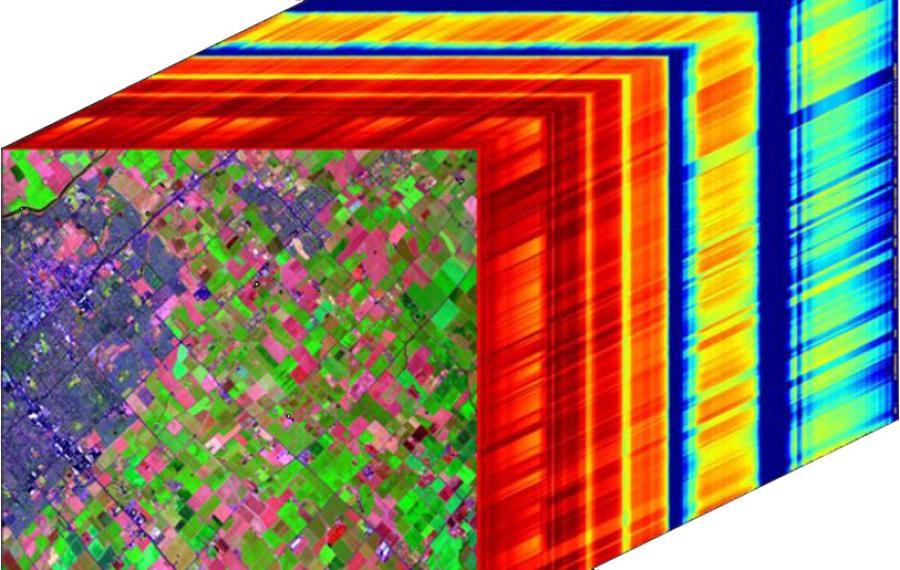 Imaging spectrometer data cube over an agricultural landscape, with a false-color image on the front face and hundreds of wavelength bands behind it.