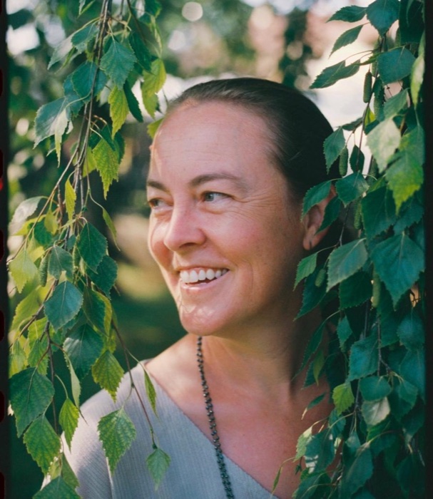 Portrait of Dana Chadwick outdoors, framed by birch leaves.